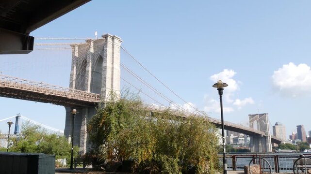 Brooklyn Bridge from Manhattan Downtown, New York City, United States. Bridge to Dumbo from esplanade pier park in NYC USA. American architecture, famous tourist landmark. Waterfront urban promenade.