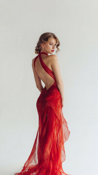 Elegant young woman in a flowing backless red dress
