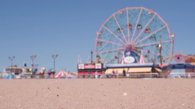 Coney Island sandy beach in Brooklyn, New York, United States. Boardwalk near retro luna park. Ferris wheel in american amusement park on ocean coast. Waterfront summer holiday promenade in NYC, USA.