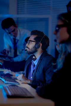 Team monitors a large world map display in a high-tech security operations control room during a busy night shift.
