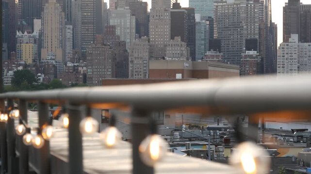 New York City Manhattan Midtown skyline from Queens, United States. Skyscraper buildings architecture, cityscape from rooftop in Long Island, Hunters Point. Light bulbs garland on roof, urban sunset.