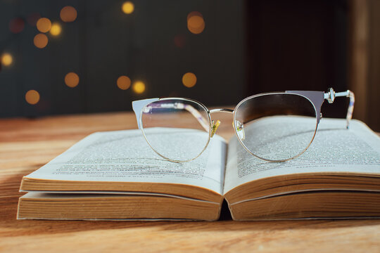 Glasses on an open book on a wooden table, concept of studying and education