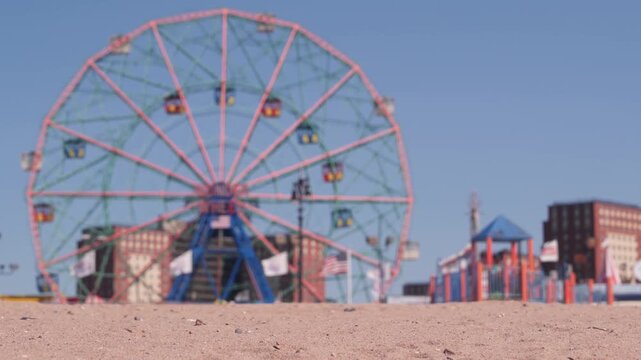 Coney Island sandy beach in Brooklyn, New York, United States. Boardwalk near retro luna park. Ferris wheel in american amusement park on ocean coast. Waterfront summer holiday promenade in NYC, USA.