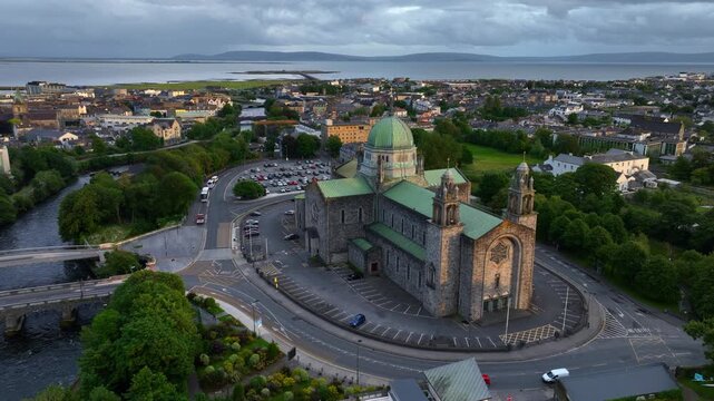 orbiting drone view of Galway at sunset with Galway cathedral and Salmon Weir Bridge over the river Corrib, Galway bay and historic town aerial view, Irish city of Galway, travel in Ireland