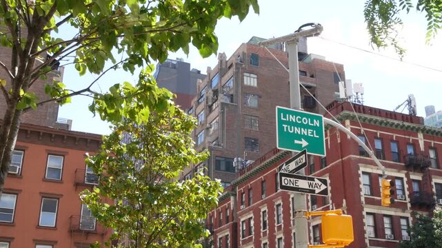 New York City Lincoln Tunnel street sign in Manhattan Midtown, United States. Urban road sign in american city, traffic sign in NYC. Red brick building architecture, Chelsea district near Hudson Yards