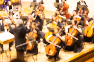 Blurred background of a symphony orchestra with conductor performing on stage in a concert hall © Ruslan