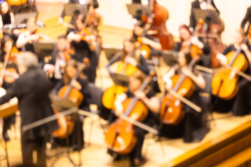 Blurred background of a symphony orchestra with conductor performing on stage in a concert hall © Ruslan
