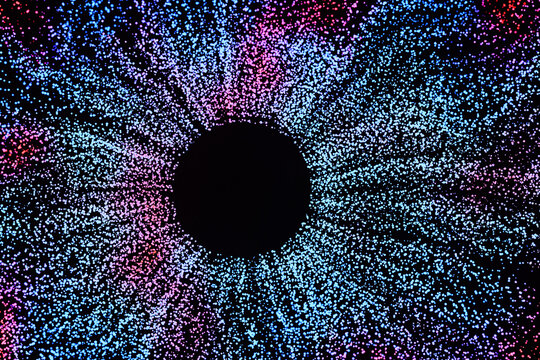 Abstract futuristic background featuring a central black circle surrounded by a burst of glowing blue and purple particles, resembling a digital iris, cosmic black hole, or data visualization.