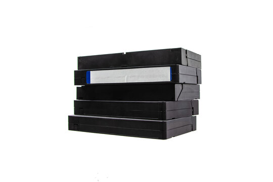 A stack of old black retro VHS video cassettes isolated on a bright white back