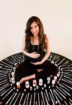Pregnant woman surrounded by fertility needles and syringes