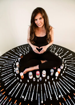 Pregnant woman surrounded by fertility needles and syringes
