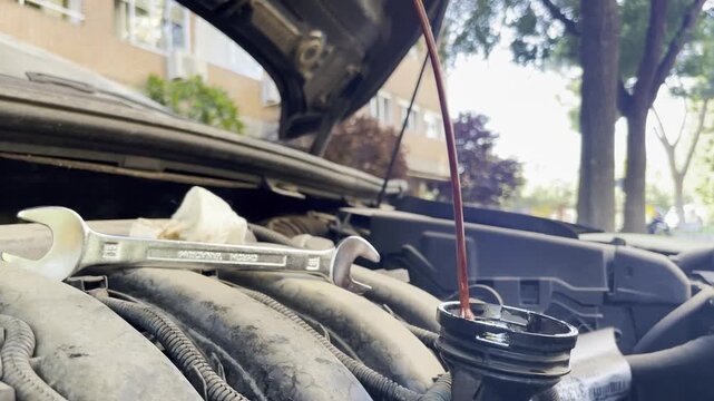 Mec&aacute;nico revisando motor y varilla de nivel de aceite, lubricaci&oacute;n, viscosidad, tap&oacute;n de dep&oacute;sito y mantenimiento veh&iacute;culo con trapo y limpieza