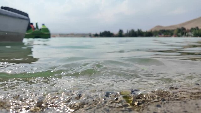 Low Angle View of Clear Lake Water Ripples with Pedal Boat in Background