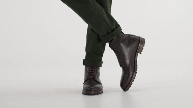 Man in brown leather boots and green pants dancing and walking isolated on a white background