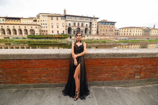 Beautiful stylish bride in a black dress stands on the embankment in Florence, Italy