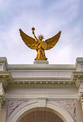 Obraz premium Golden statue crowns ceremonial arch. One nation under God. Patriotic golden statue above columns. Historic golden statue honors liberty. Golden statue stands over gateway.
