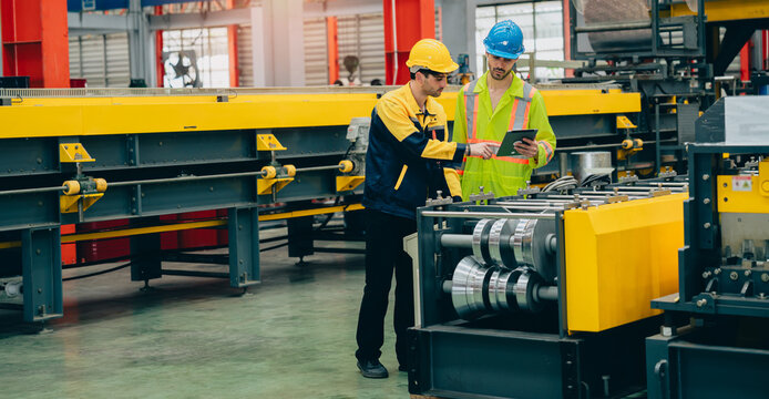 Industrial engineer factory worker safety helmet tablet metal machine manufacturing floor teamwork inspection