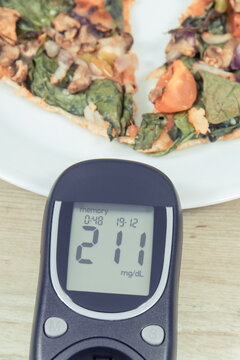 Glucose meter for sugar level control and piece of vegetarian pizza. Nutrition and eating fast food during diabetes