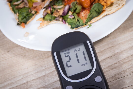 Glucose meter with very high result of sugar level and fresh baked vegetarian pizza. Nutrition during diabetes