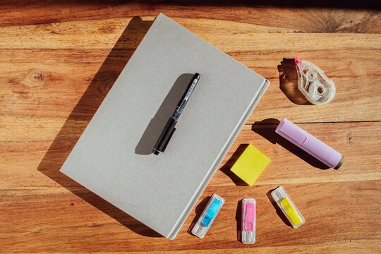 Desk organization and productivity concept with a closed journal, highlighter and sticky notes under natural sunlight