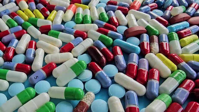 Colors and shapes of different pills and capsules on a flat surface in bright light during the day