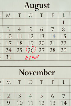 Exam date marked with a red circle on a wall calendar, student planning concept