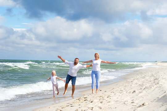 A little girl and her parents walk on the beach on the Baltic Sea in Lithuania
