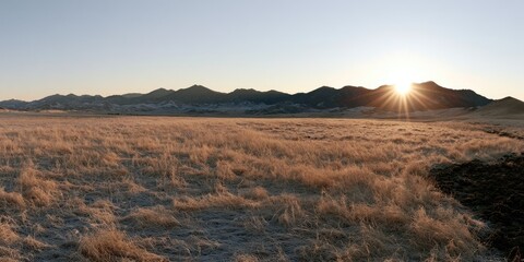 Naklejka premium Golden sunrise over frost-covered prairie and distant mountains
