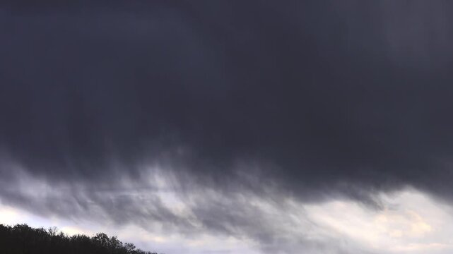 Dark rain cloud and heavy downpour on a green hillside.