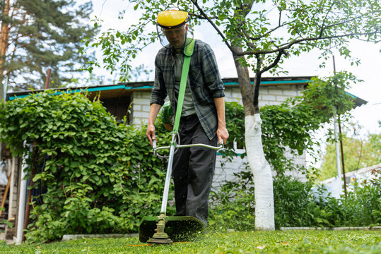 Man trimming grass in a lush green garden