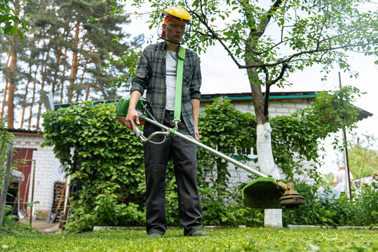 Gardener using a grass trimmer in a backyard