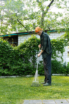 Man raking the grass in a sunny backyard garden