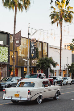 Vertical photo of a beige restored 1956 Chevrolet Bel Air in California with palm trees in the background, capturing classic American car culture