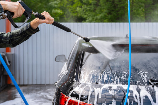 Man washing car with pressure washer at self service bay