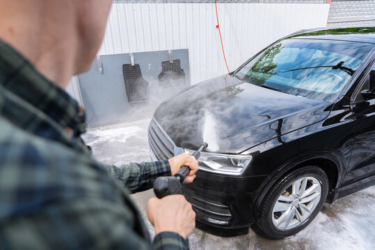 Man pressure washing black car at self service car wash