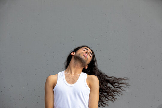 Middle Eastern man with vitiligo posing against gray wall
