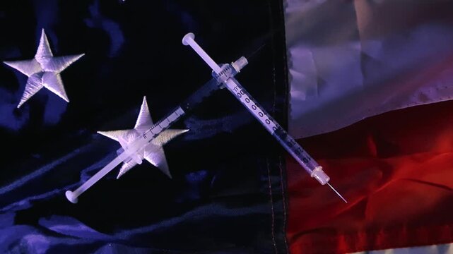 Two crossed syringes lying on the American flag representing the United States healthcare system, the covid 19 pandemic response, mandatory vaccination policies, and the opioid crisis
