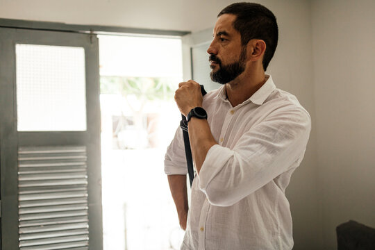 Authentic lifestyle moment of a man dressing at home before leaving, emphasizing personal style and preparation.