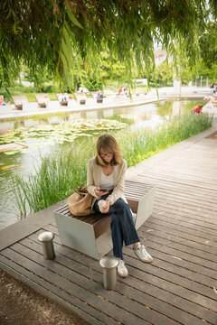 Mature business woman checking her smartphone during a coffee break in a city park