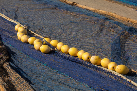 Fishing net with yellow floats drying on sandy shore