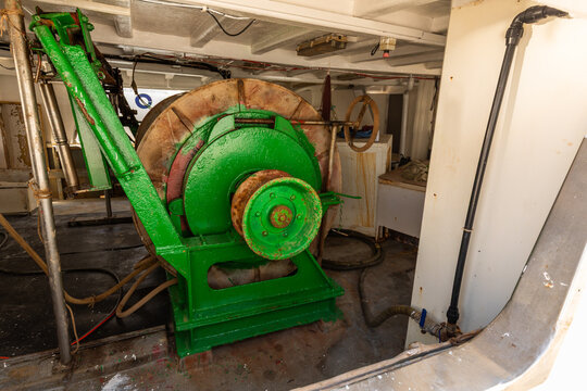 Green winch machinery inside working fishing boat hold