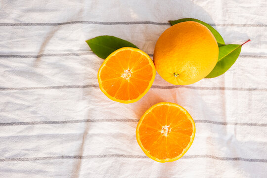 Fresh oranges on striped cloth surface