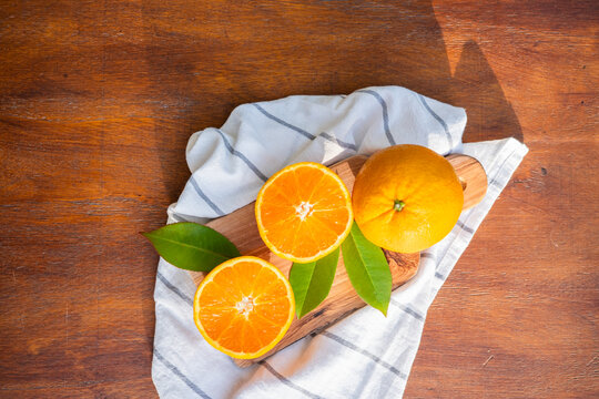 Fresh orange halves on cutting board with leaves