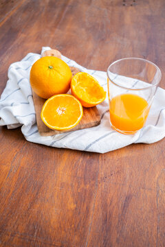 Fresh orange juice on wooden table with whole and sliced oranges