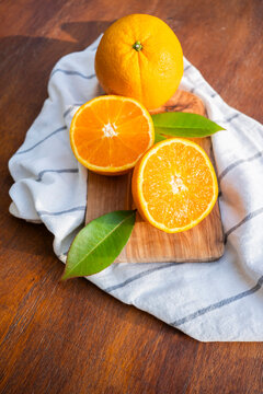 Fresh oranges on a wooden board with striped cloth