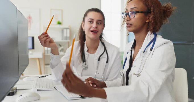 Doctors physicians colleagues consultation by computer for analysis. They review records in a clinic coordinate care and update EHR systems for accuracy. Clear concept of teamwork and diagnosis.