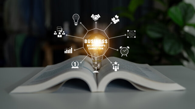 Illuminated Concept of Business Relationships and Connections with Icons Emerging from an Open Book on Table in Modern Office Environment Quark.