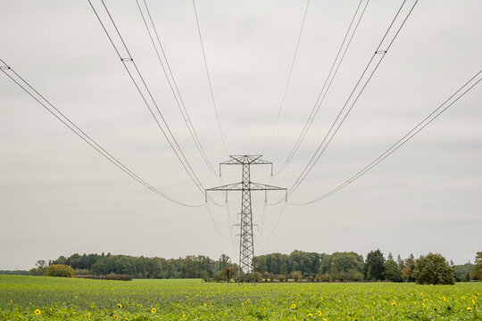 High voltage power line tower over green rural meadow