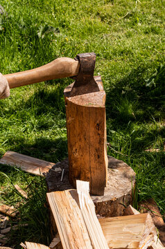 Close-up of axe chopping wood on stump in sunny yard