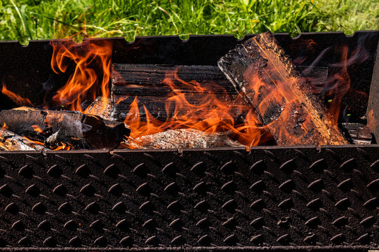Open fire in metal grill with burning logs outdoors